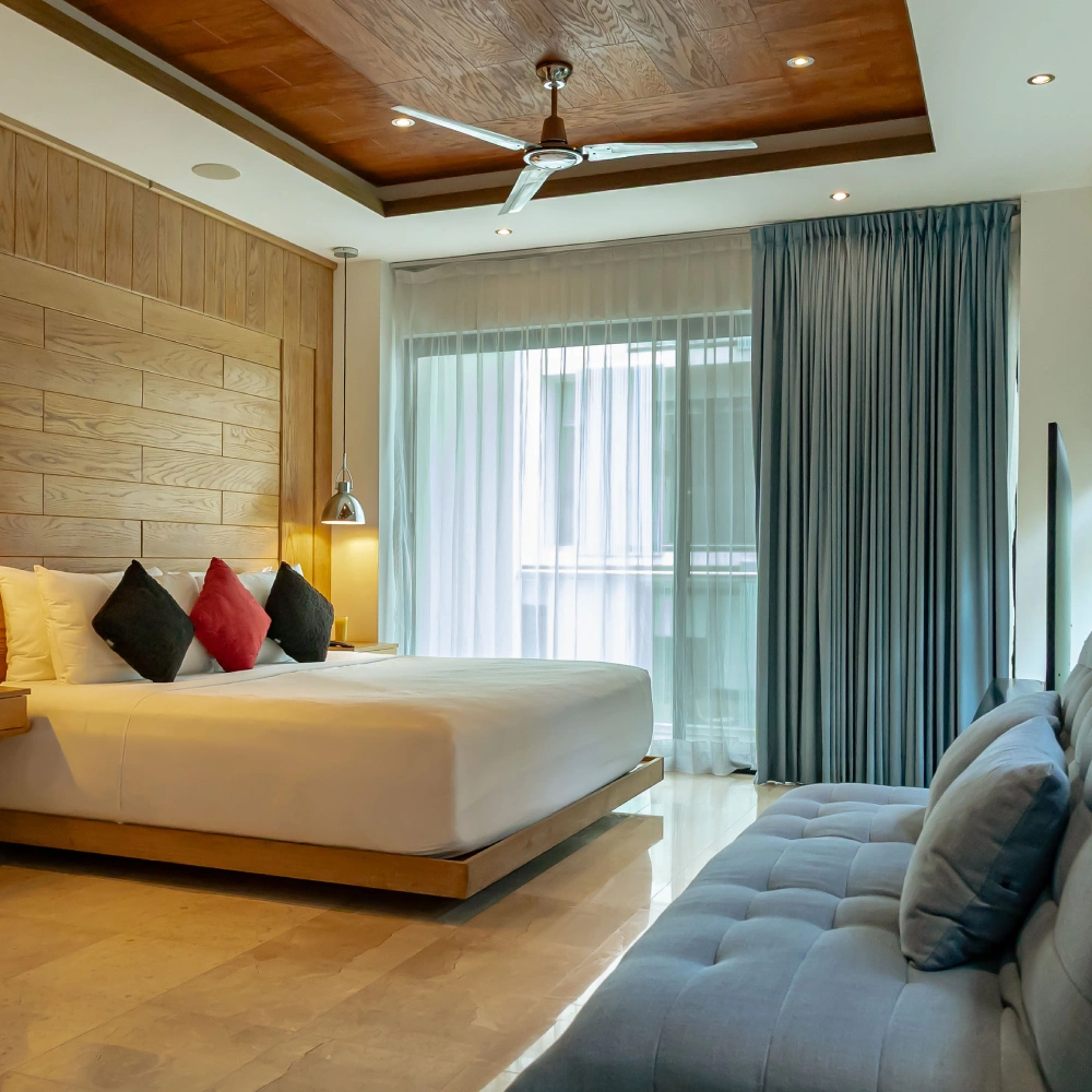 Modern bedroom with bedgray sofa, and curtains next to a large window